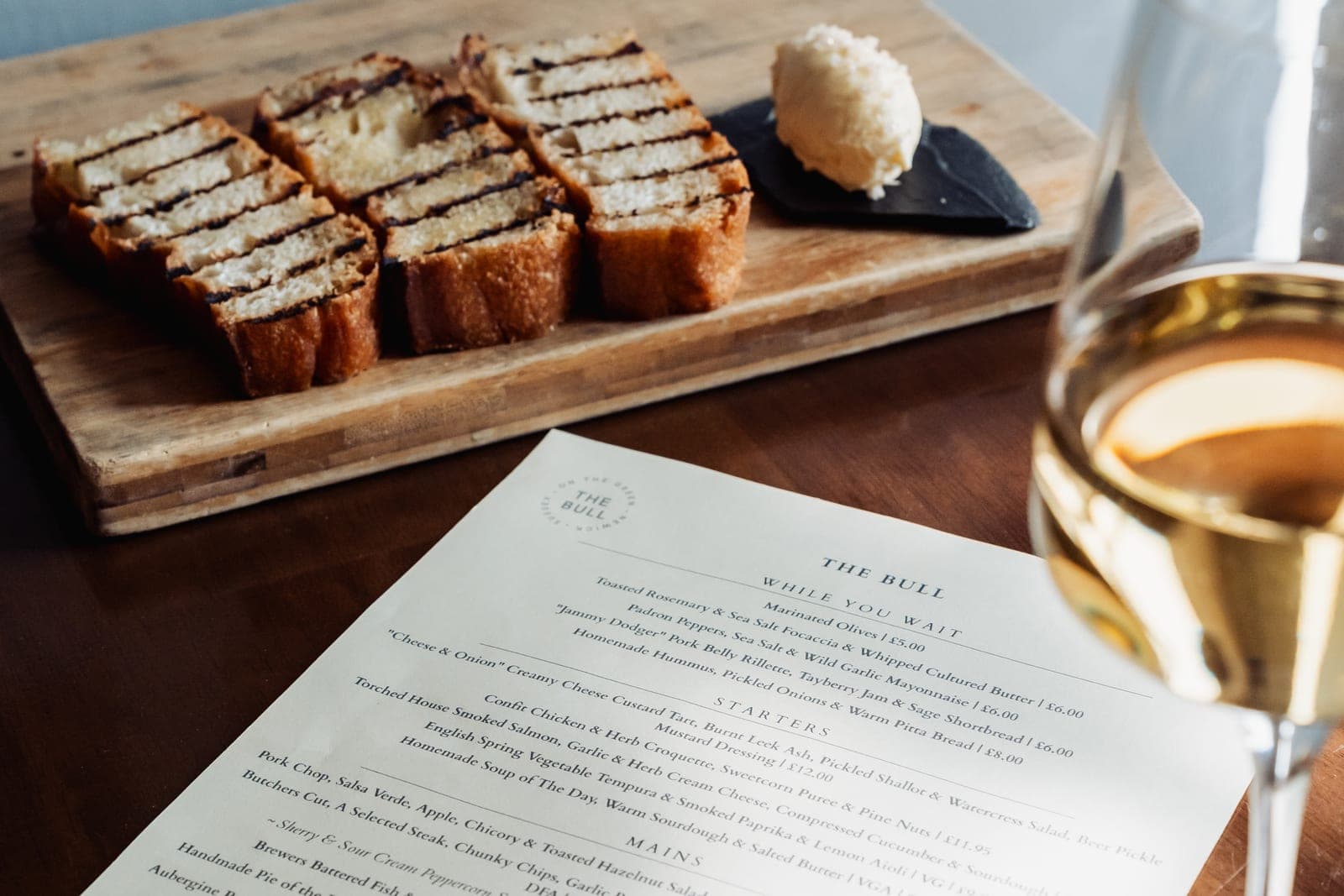 The Bull menu with a glass of wine and warm sourdough